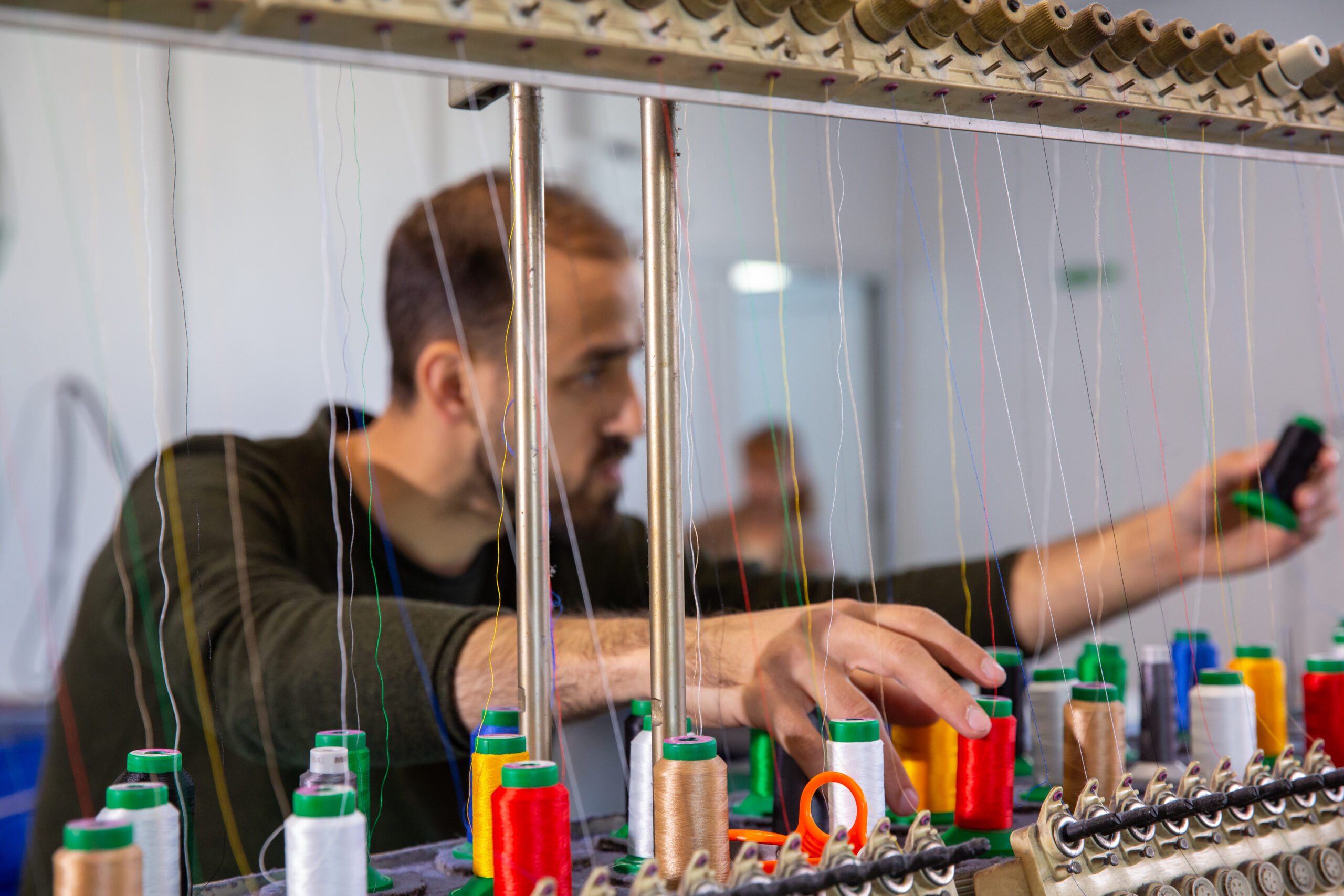 Worker at the textile factory that arranges the multicolored yarn reels. Professional worker